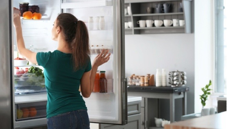 Donna cerca qualcosa nel frigo aperto in cucina