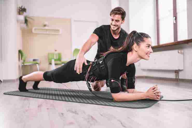 ragazza in plank prova l'allenamento con gli elettrodi