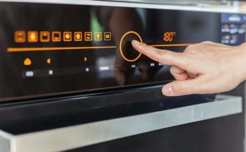 mano di una persona preme su modalità di riscaldamento forno