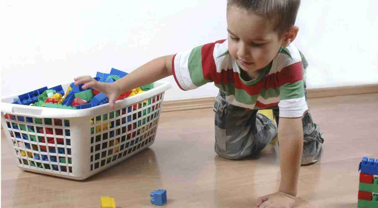 Bambino che prende mattoncini dalla cesta dei giocattoli 