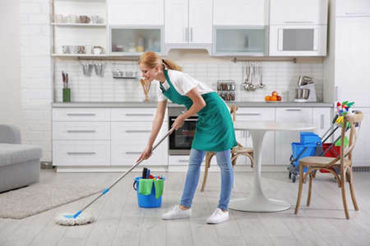donna pulisce il pavimento della cuccina con scopettone