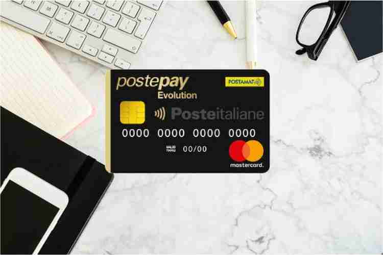 Carta Postepay evolution su scrivania con penna, tastiera, taccuino e occhiali