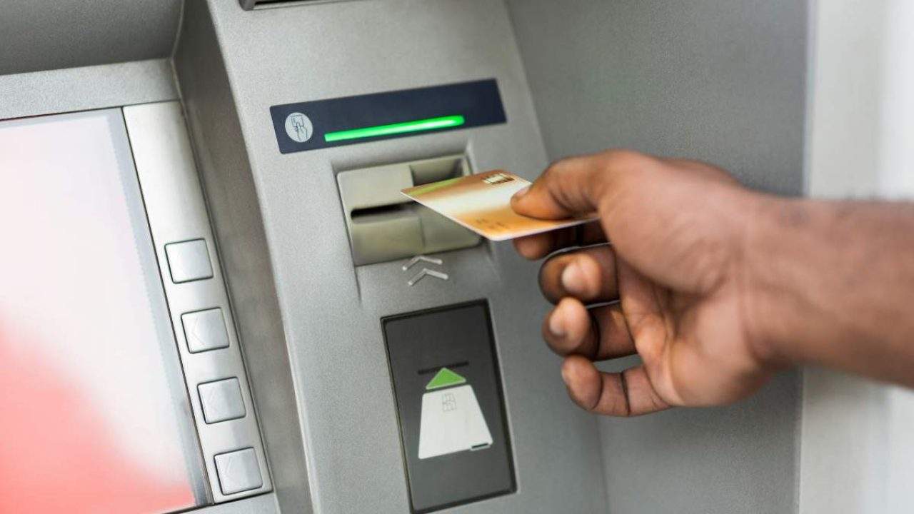 uomo inserisce carte di credito al bancomat