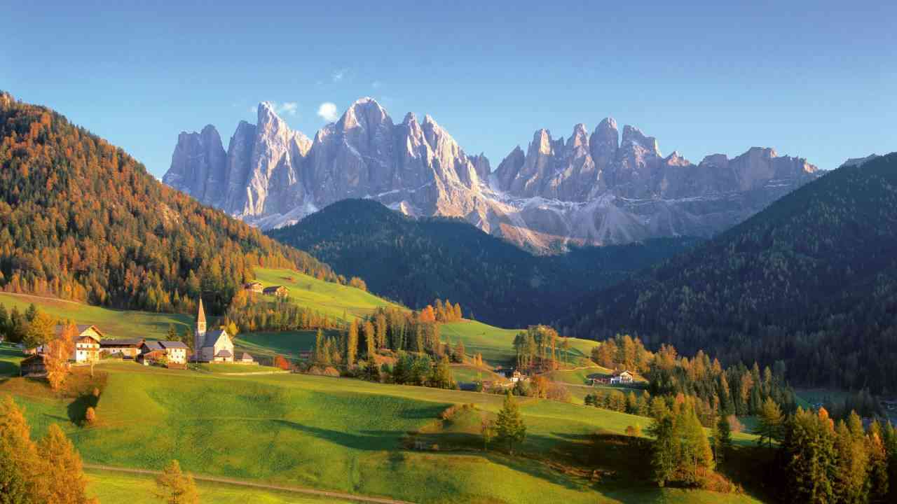 paesaggio paesino dentro la vallata con dietro le Dolomiti