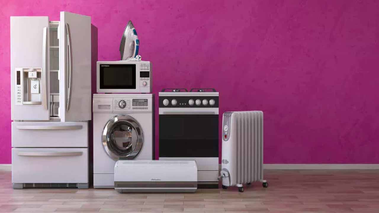 frigorifero, lavatrice, forno, forno a microonde, ferro da stiro, condizionatore, stuffa eletrica messi in fila su parete viola