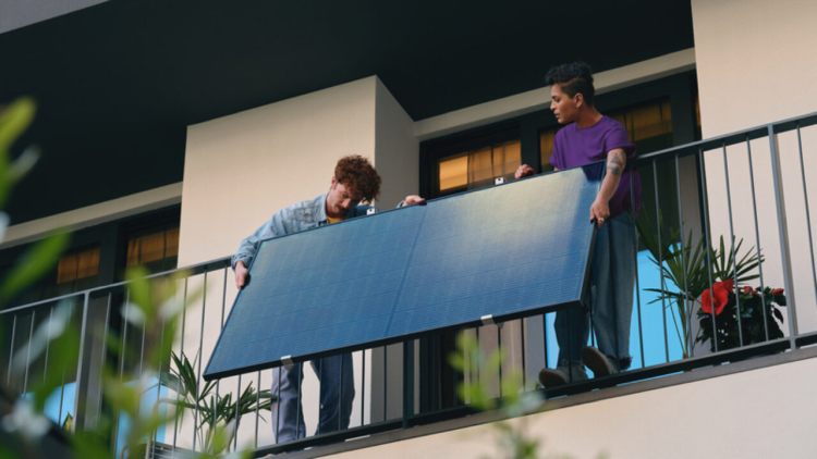 un uomo e una donna installano un panello fotovoltaico sul balcone di casa