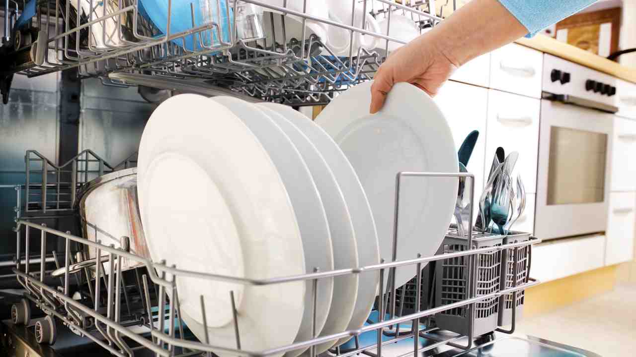 donna prende i piatti puliti dalla lavastoviglie