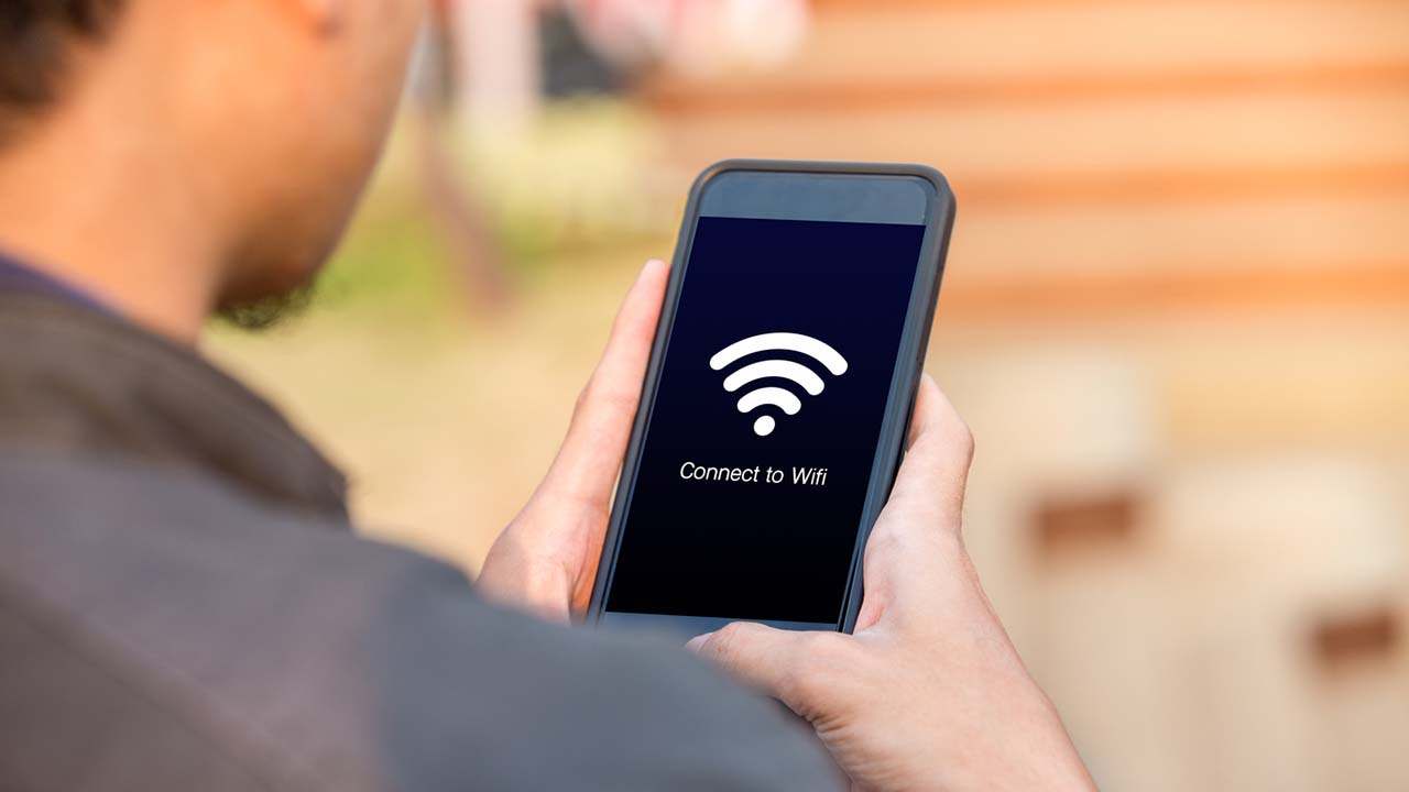 Uomo con in mano il telefono cerca di connetersi alla rete wi-fi