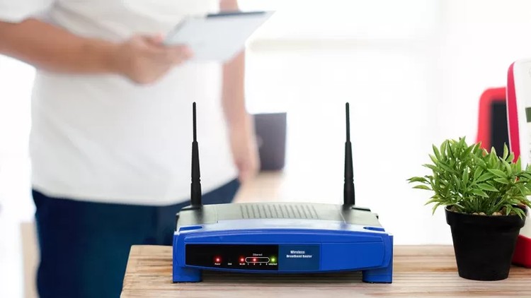 router wi-fi sul mobiletto di casa con sullo sfondo uomo che cerca di configurarlo
